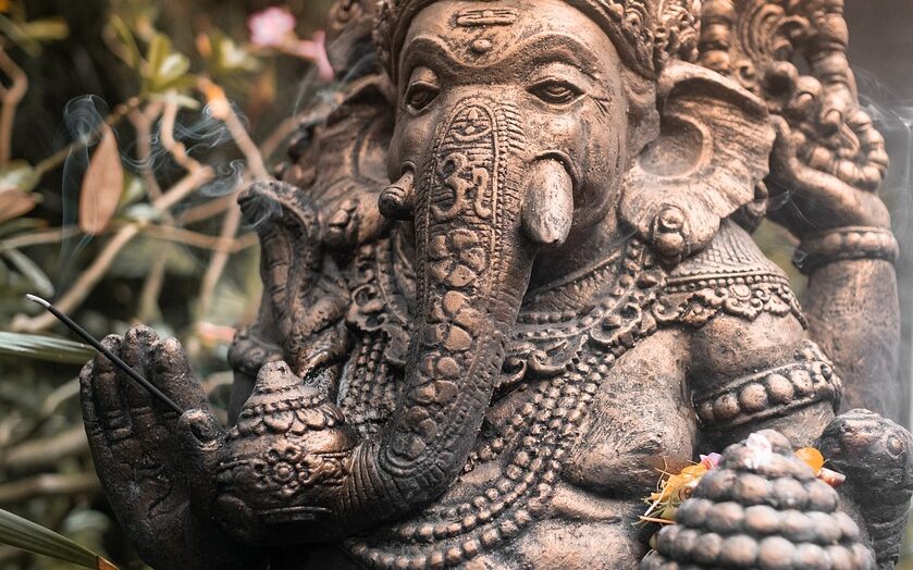 Statuette of Ganesh with burning incense stick in hand.